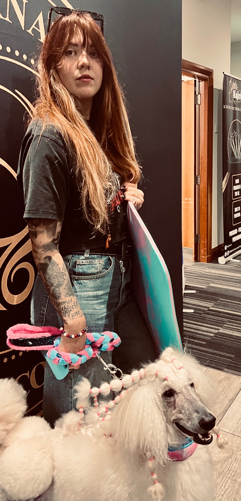 Groomer carrying the anti-fatigue mat under her arm with a white poodle